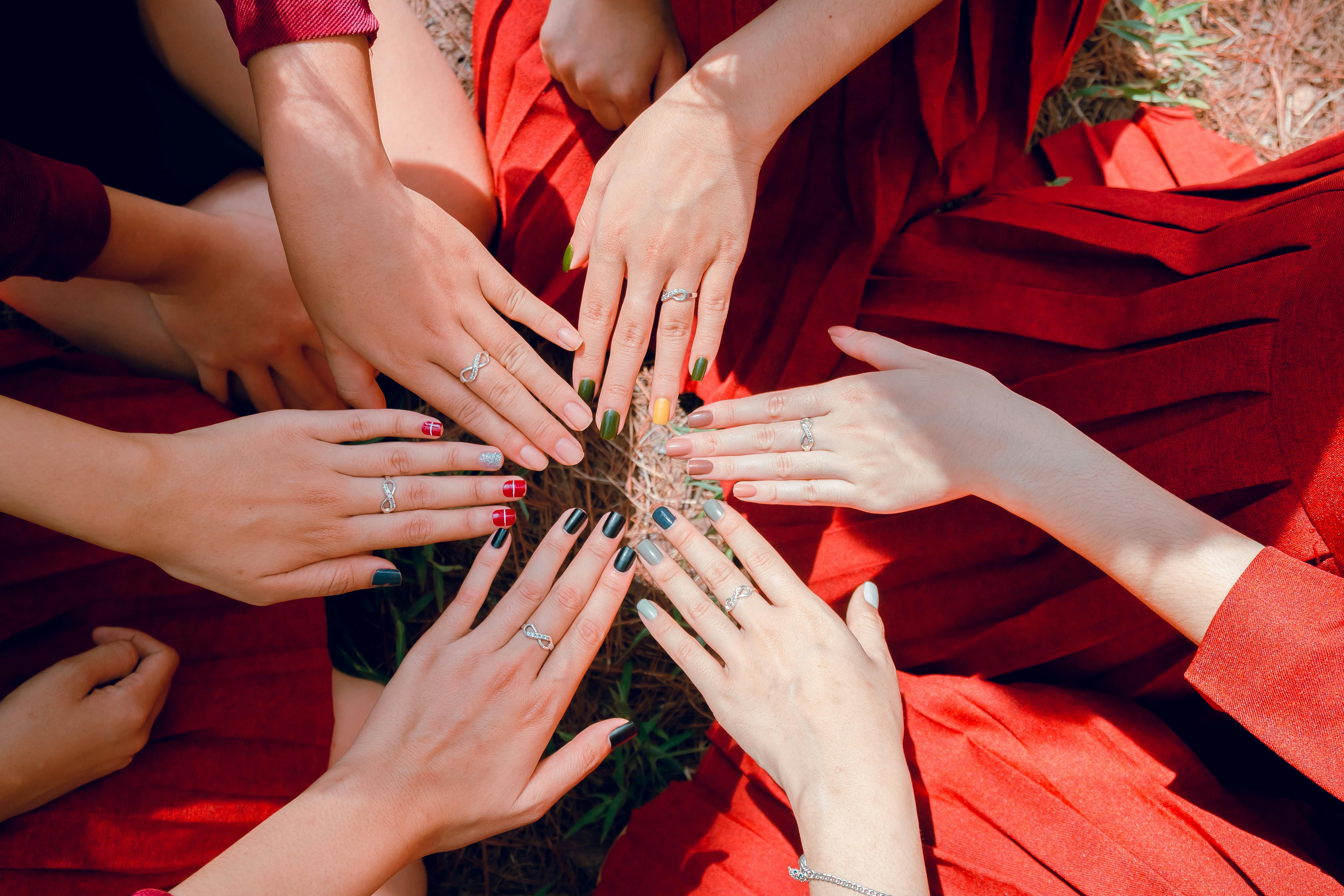 A vibrant top view of women showcasing painted nails and rings, emphasizing friendship and togetherness.